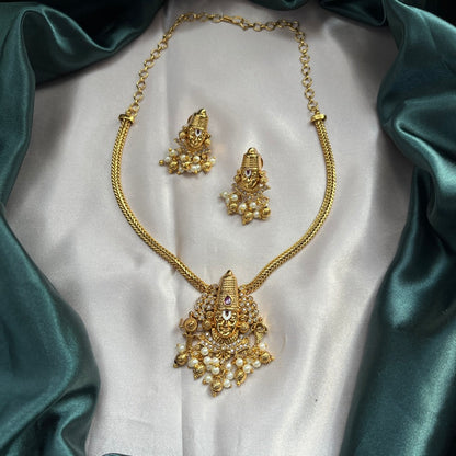 Gold necklace and earrings set on a white fabric background
