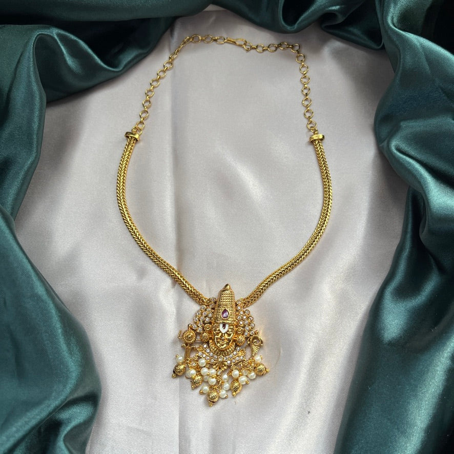 Gold necklace with a detailed pendant on a white fabric background