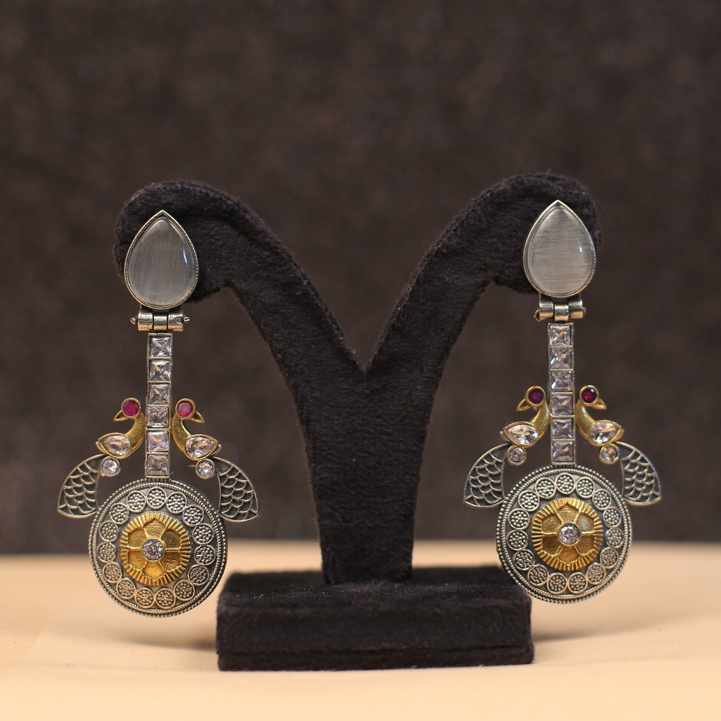 Introducing our stunning Gemstone CZ Dual tone Peacock Earrings! These gorgeous earrings feature sparkling gemstones that will catch the light and make you shine. The dual tone color adds a unique touch, while the peacock design represents beauty, luck, and prosperity. Elevate any outfit with these statement earrings!

Length - 4"

Width - 2"

Note-

Neckpiece is made of stones/beads/pearls and copper brass alloy and Mix Metal

Colour, shades, texture displayed may slightly vary from the actual product due 