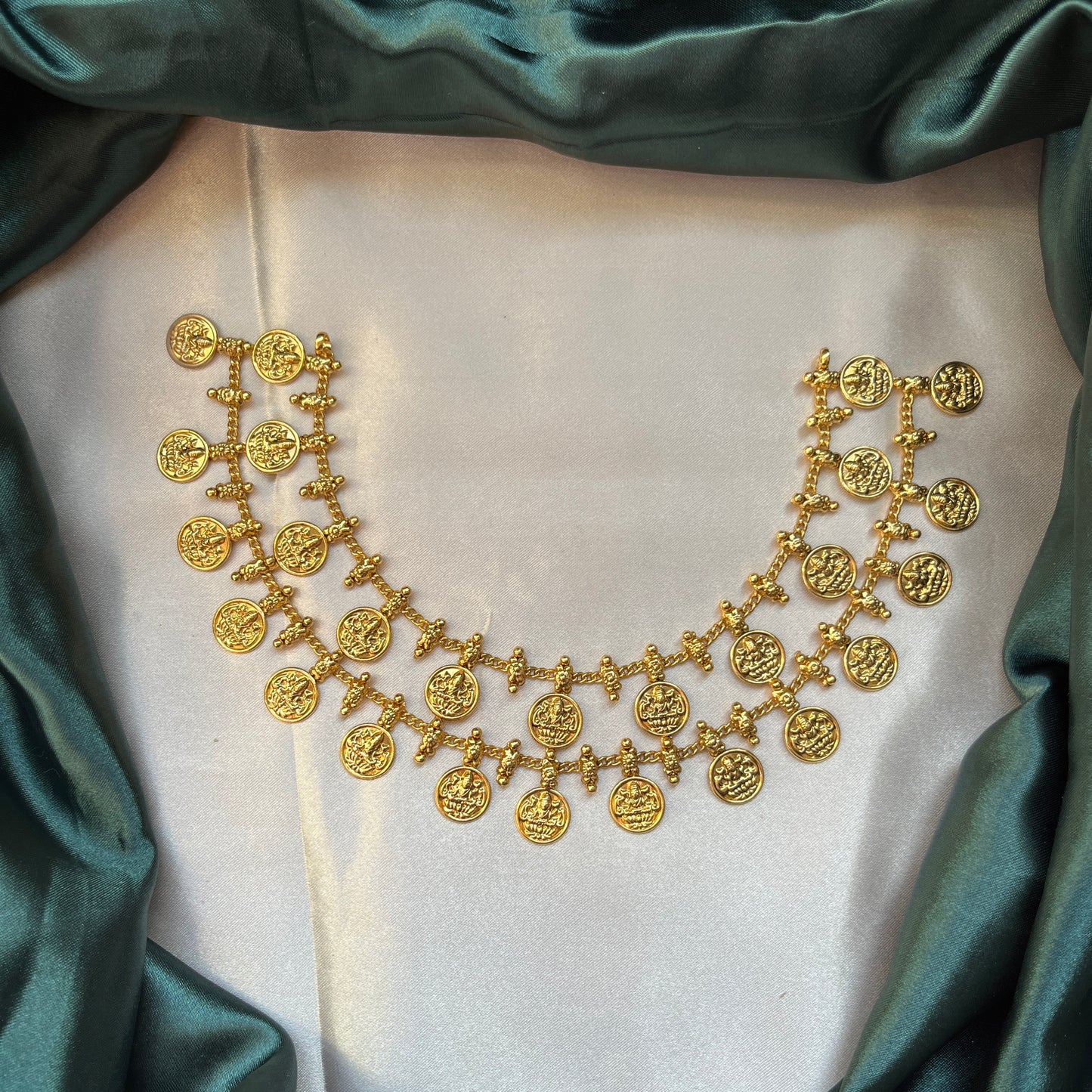 Gold necklace with coin pendants on a white fabric background